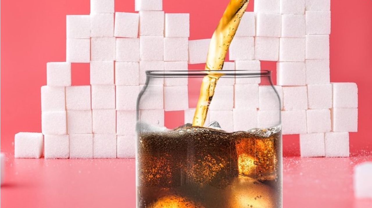 a glass of coke placed in front of sugar cubes