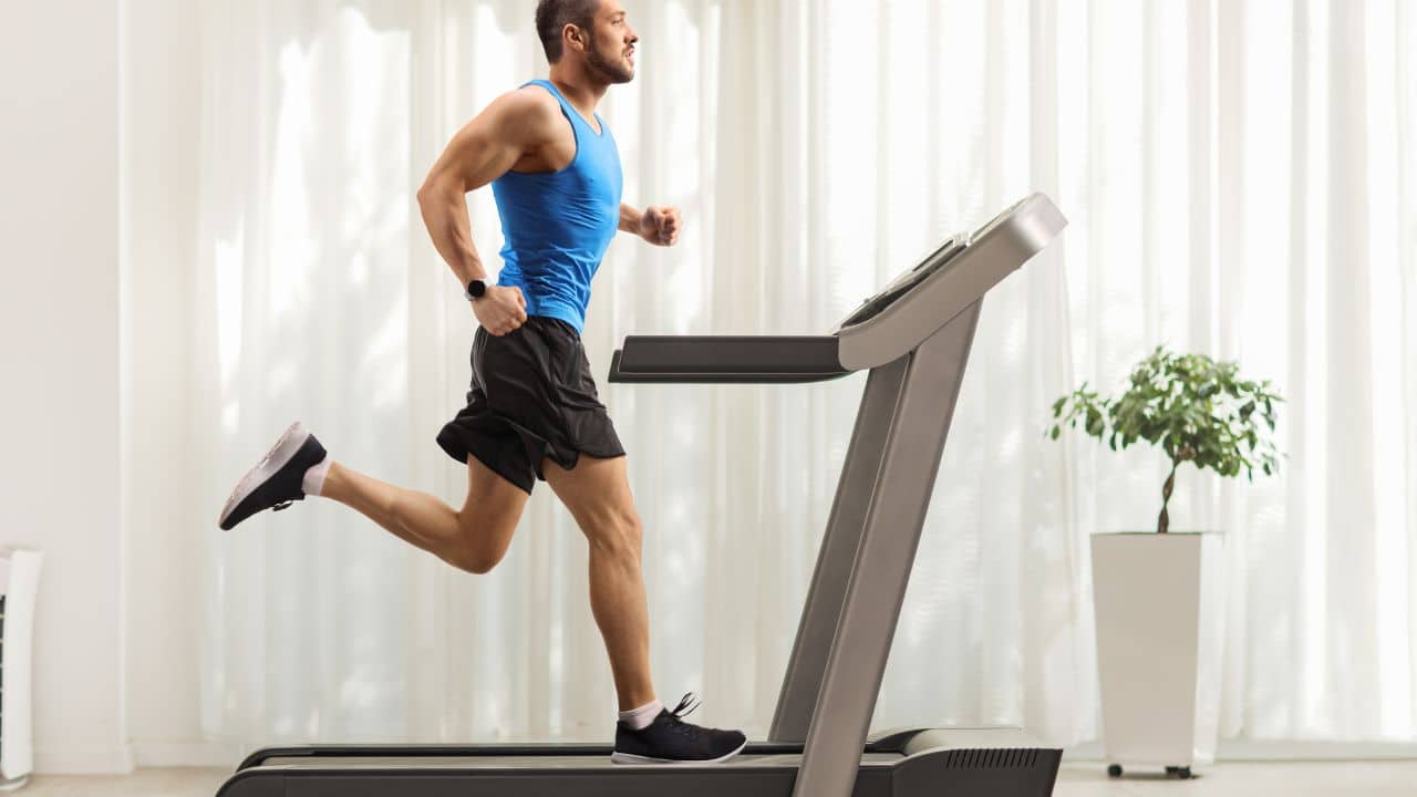 man working out on under bed treadmill in his apartment